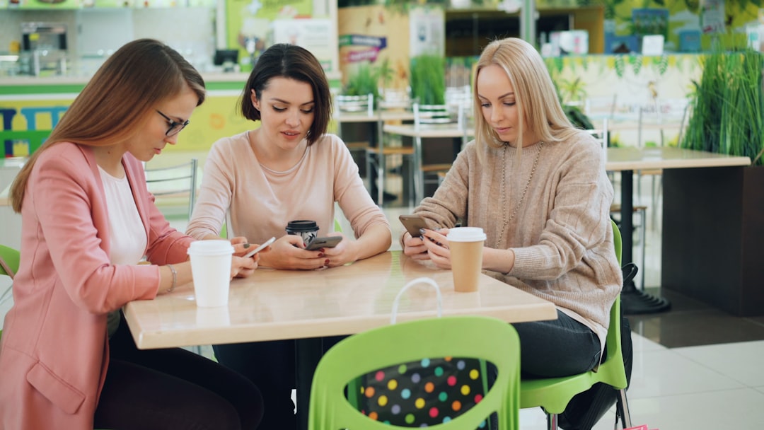 Three people checking their phones at a cafe table — four assistants, four answers about the same place