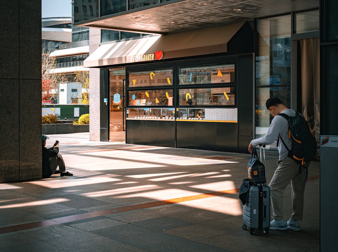 A man waiting outside a modern building — the moment a conversational query lands and an assistant has to decide which version of a fact to trust